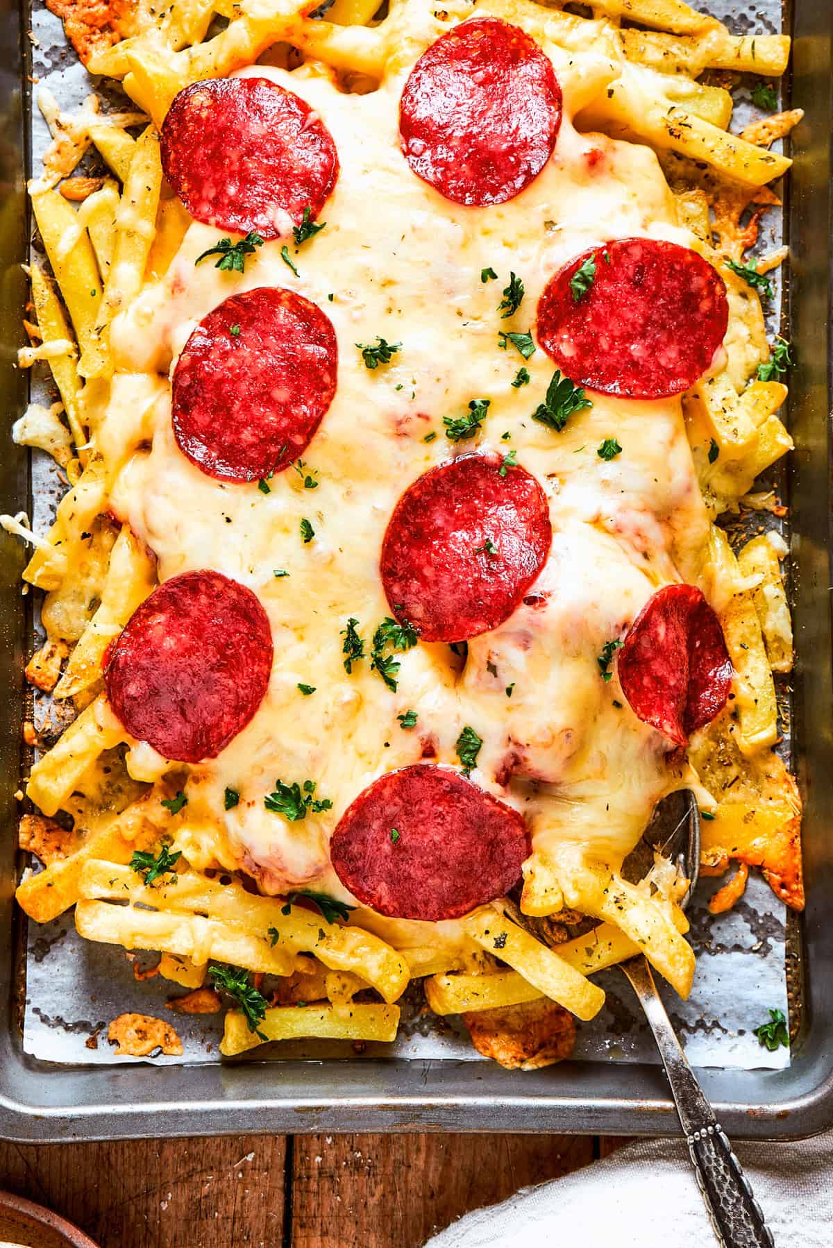 A tray of fries topped with melted cheese and slices of pepperoni.