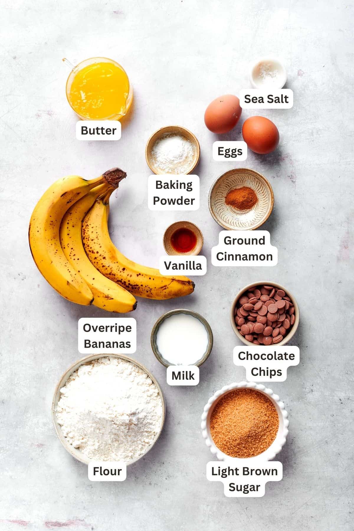 Ingredients for banana muffins recipe: bananas, vanilla, ground cinnamon, butter, baking powder, eggs, sea salt, chocolate chips, flour, brown sugar, milk.