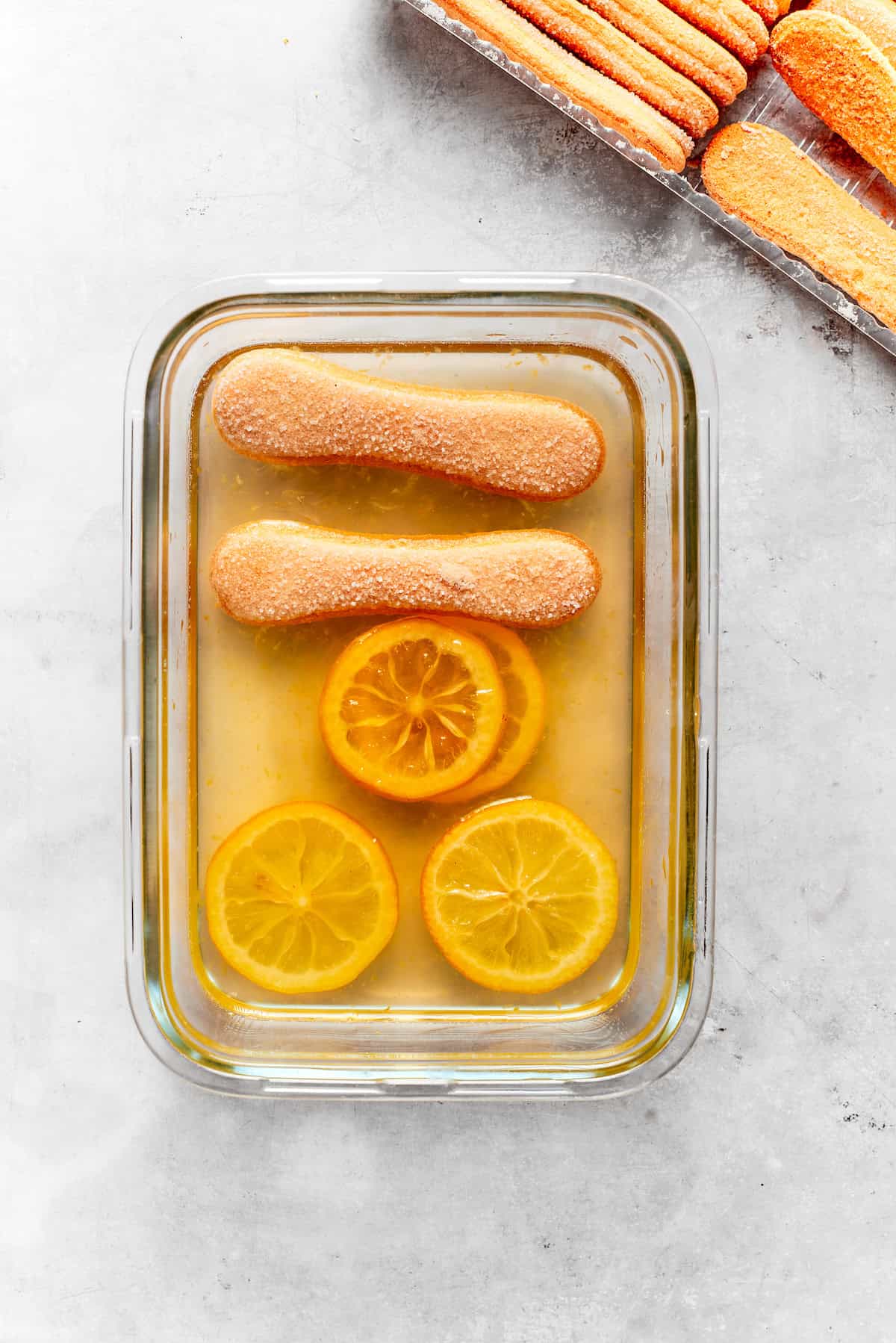 Syrup and ladyfingers are placed in a baking dish.