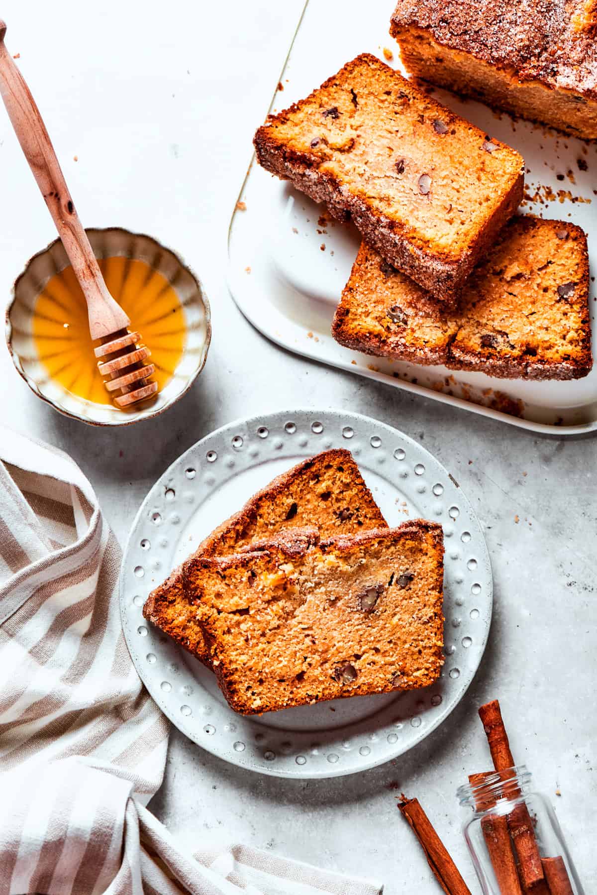 Two slices of Amish bread are served on a plate, with a bowl of honey and more bread set near the plate.