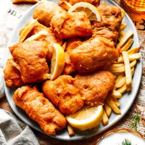 Pieces of fried fish are served on a platter over French fries.