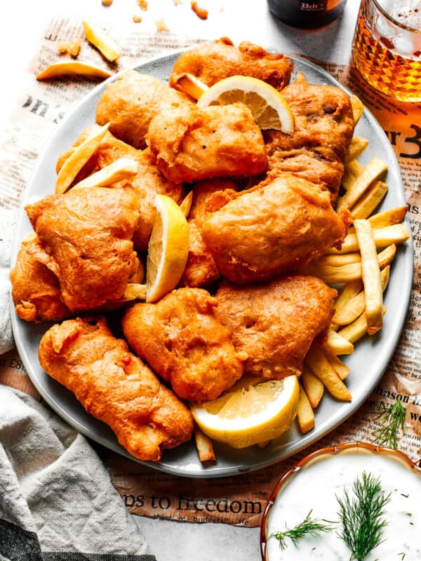 Pieces of fried fish are served on a platter over French fries.