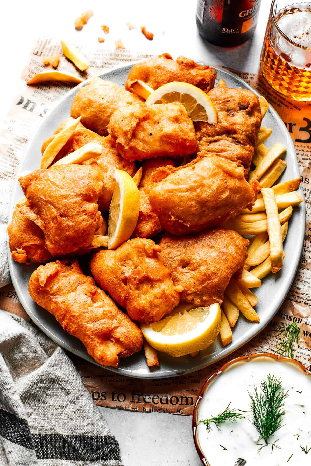 Pieces of fried fish are served on a platter over French fries.