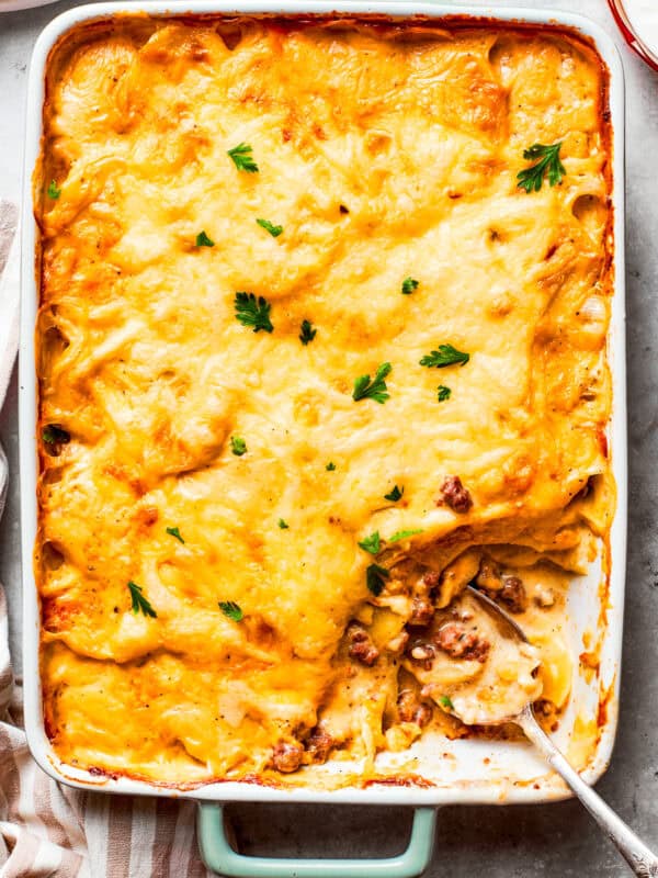 Overhead image of hamburger potato casserole in a baking dish, with a serving of it missing from the corner.