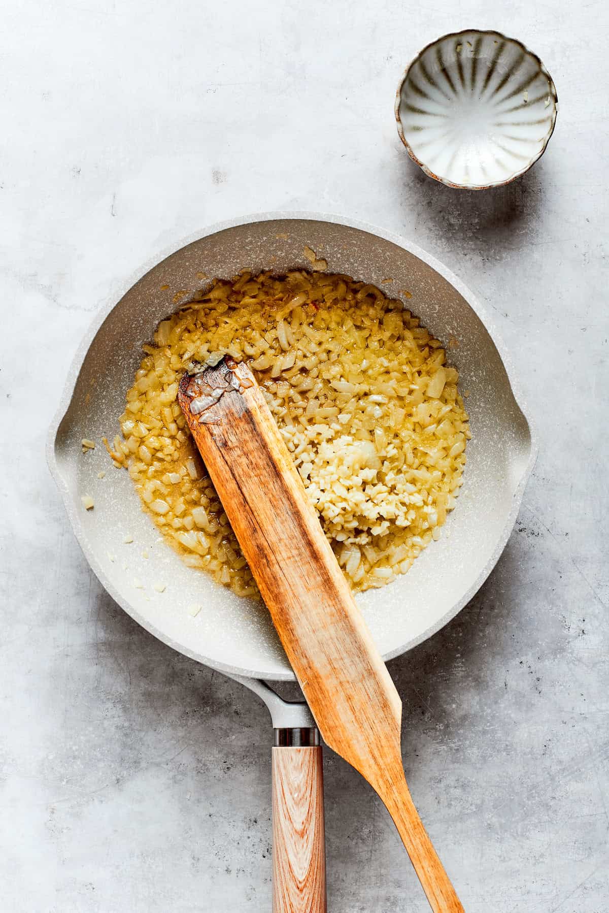 Garlic and onion are stirred in a pot.