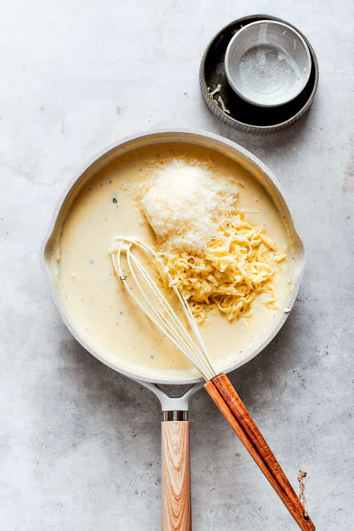 Cheeses are added to a roux in a pot.