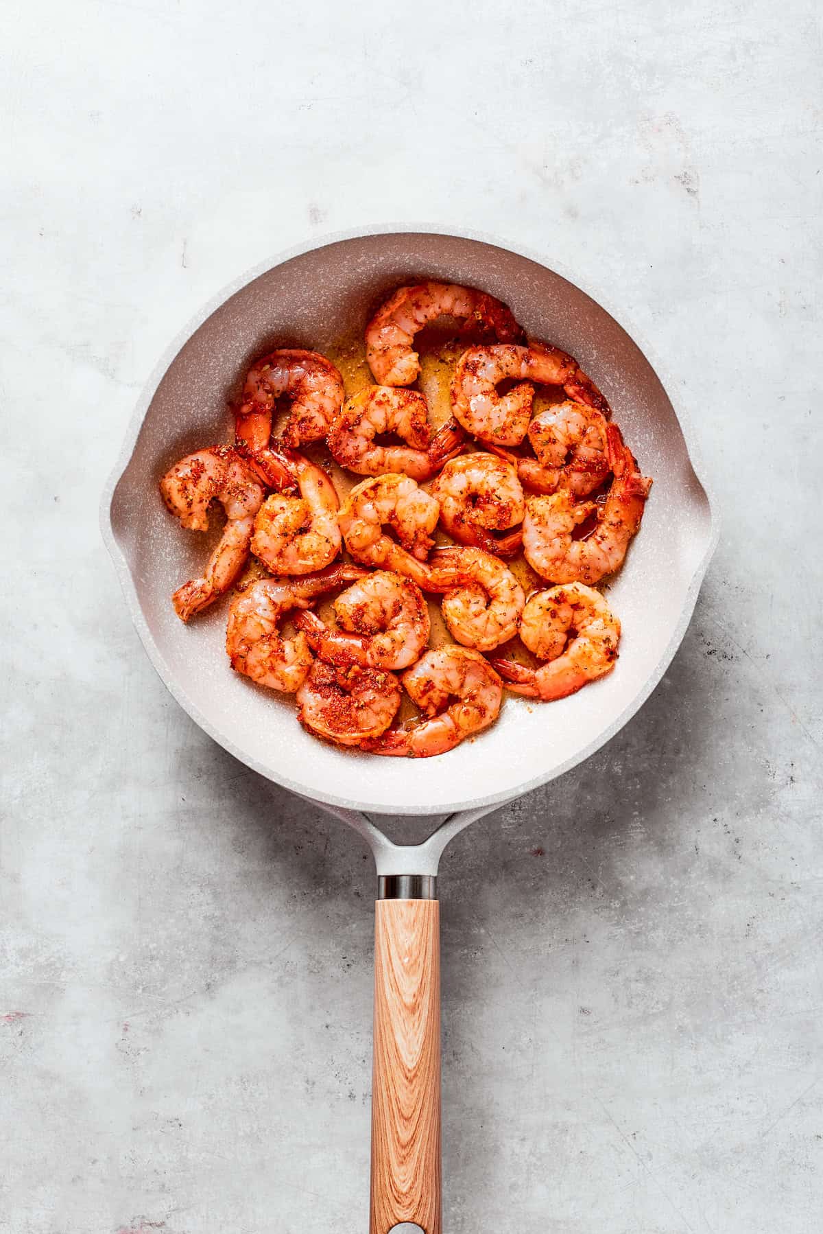 Seasoned shrimp cooks in a skillet.