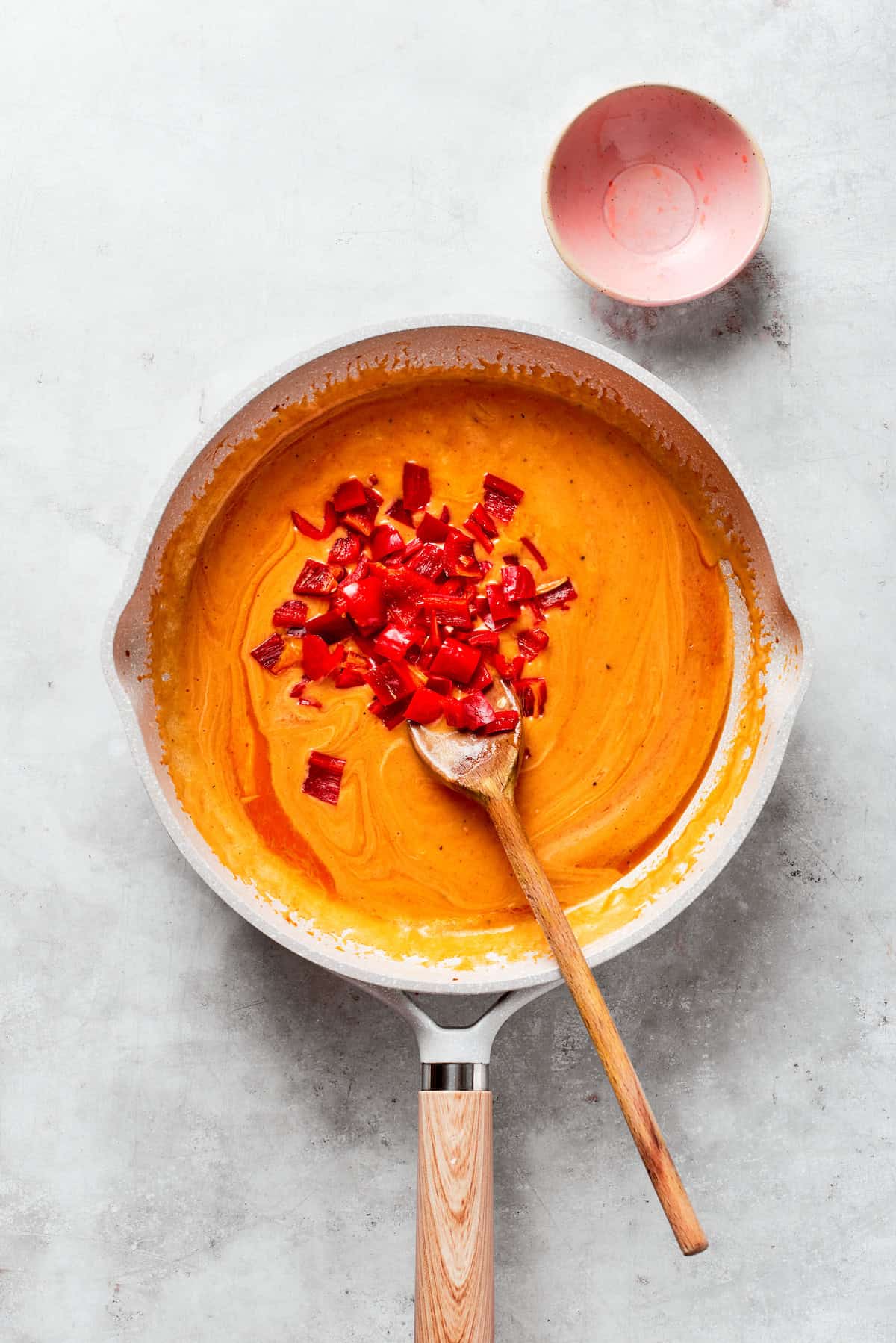 Chopped bell peppers are added to tomato sauce.