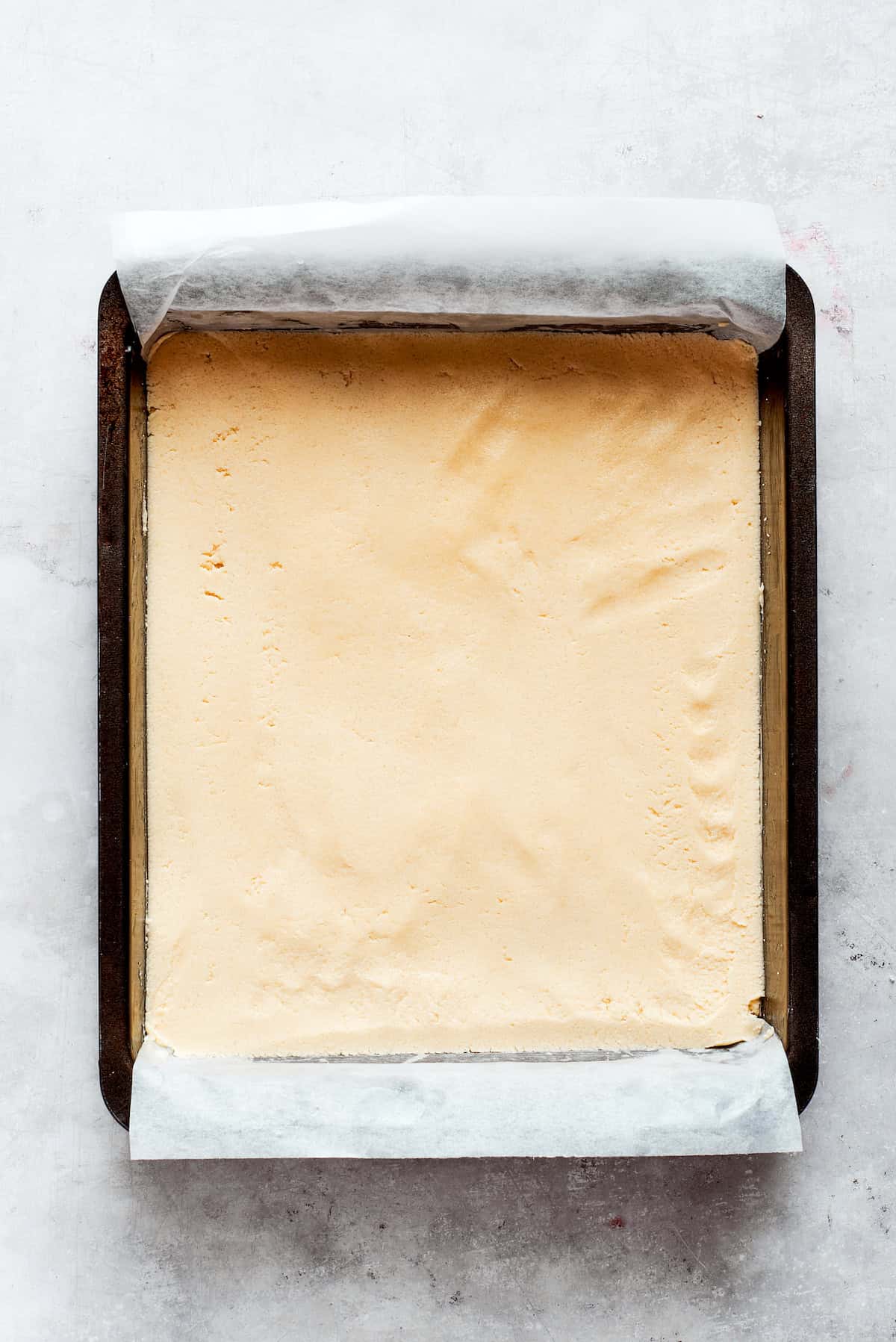 Shortbread dough is added to a lined pan.