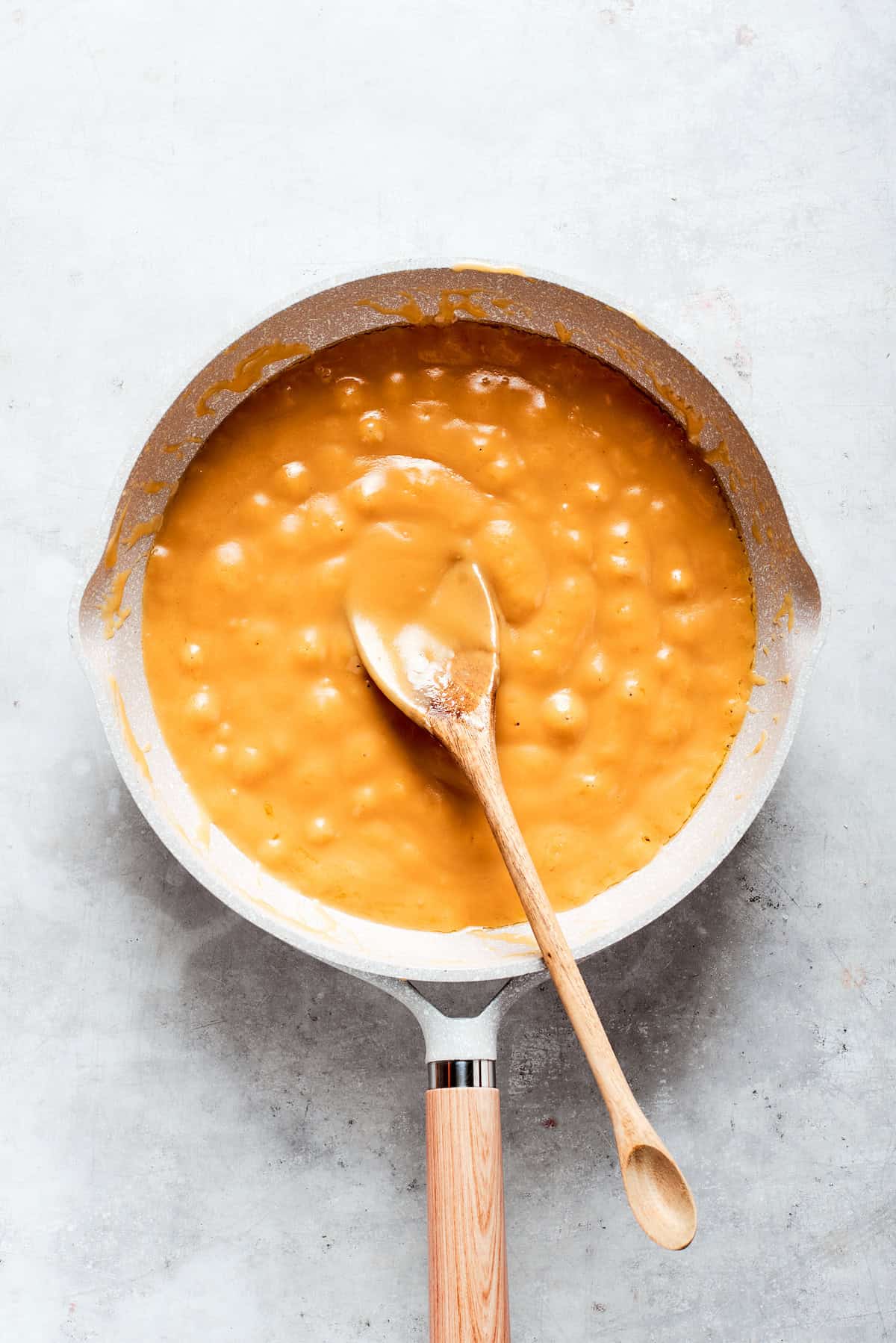 Caramel sauce is stirred until smooth in a pot.