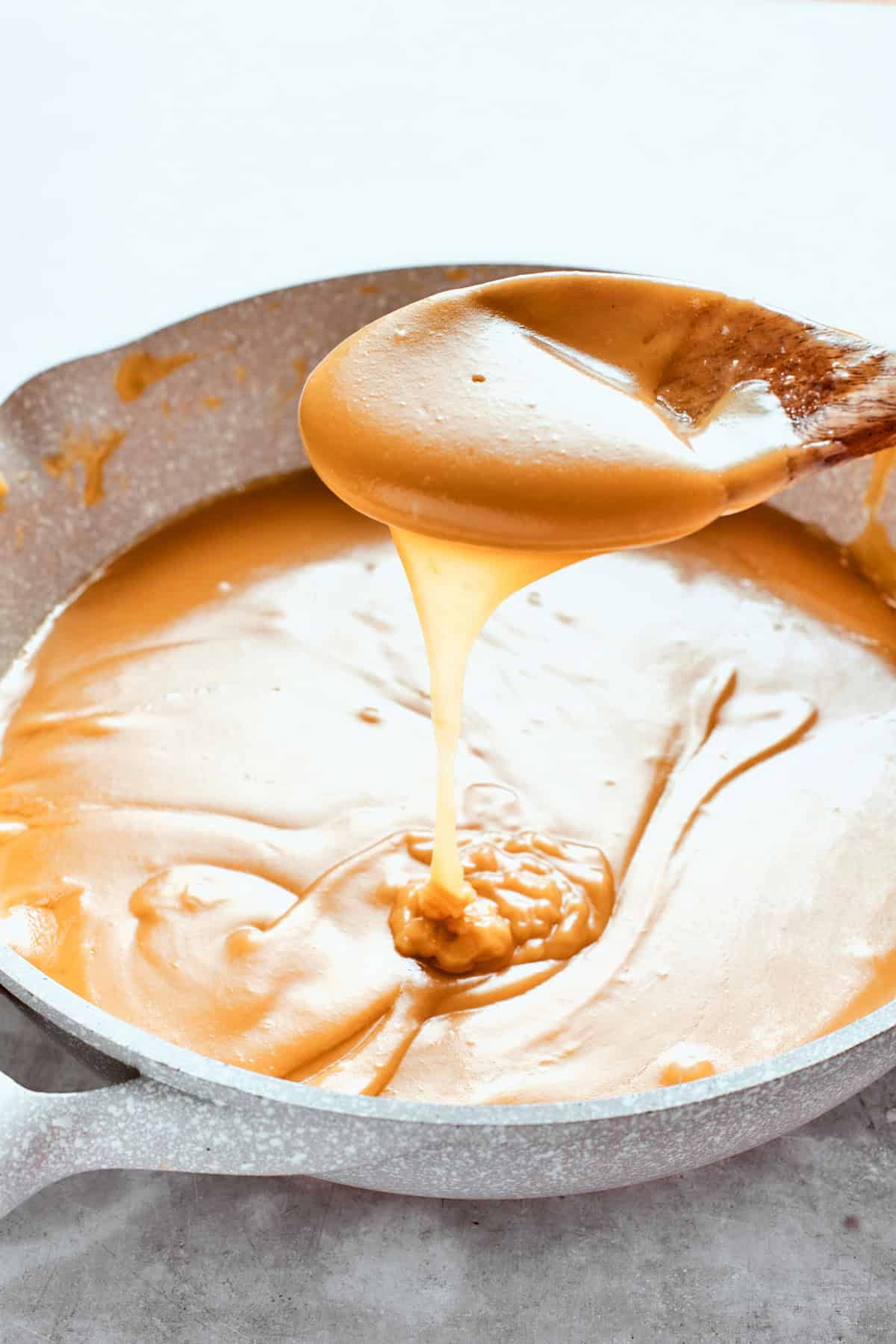 A spoon lifts up some caramel sauce.