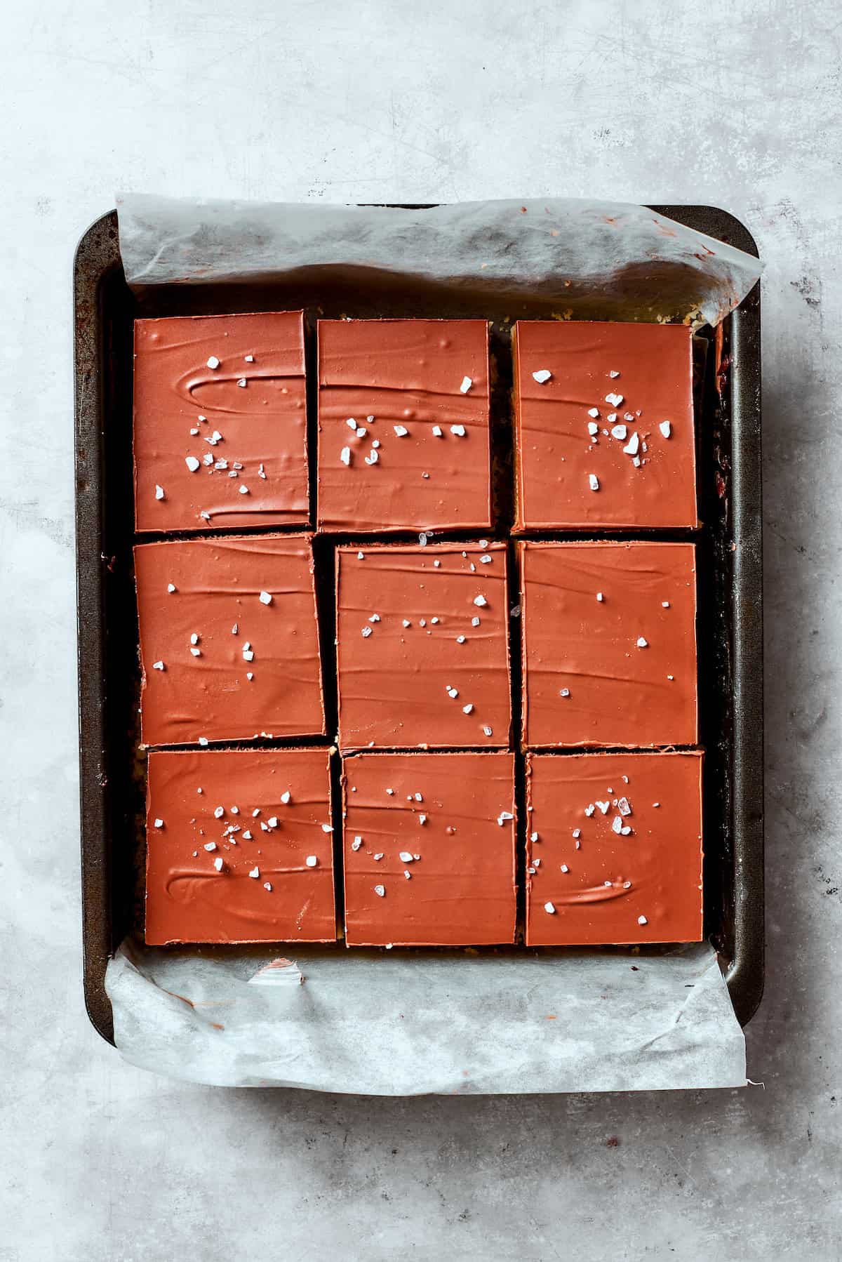 Chocolate ganache and flaky salt top a pan of millionaire bars.