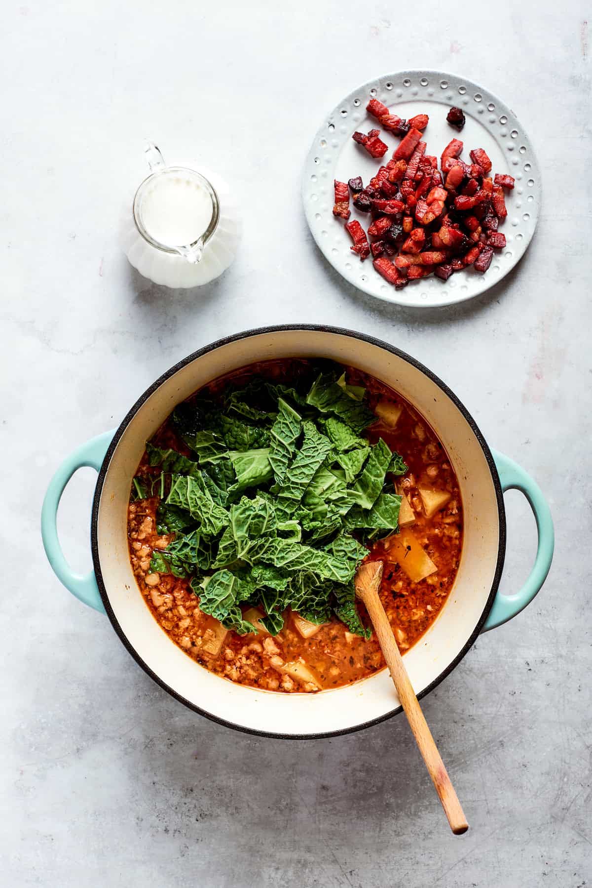 Kale is added to the top of the soup pot.