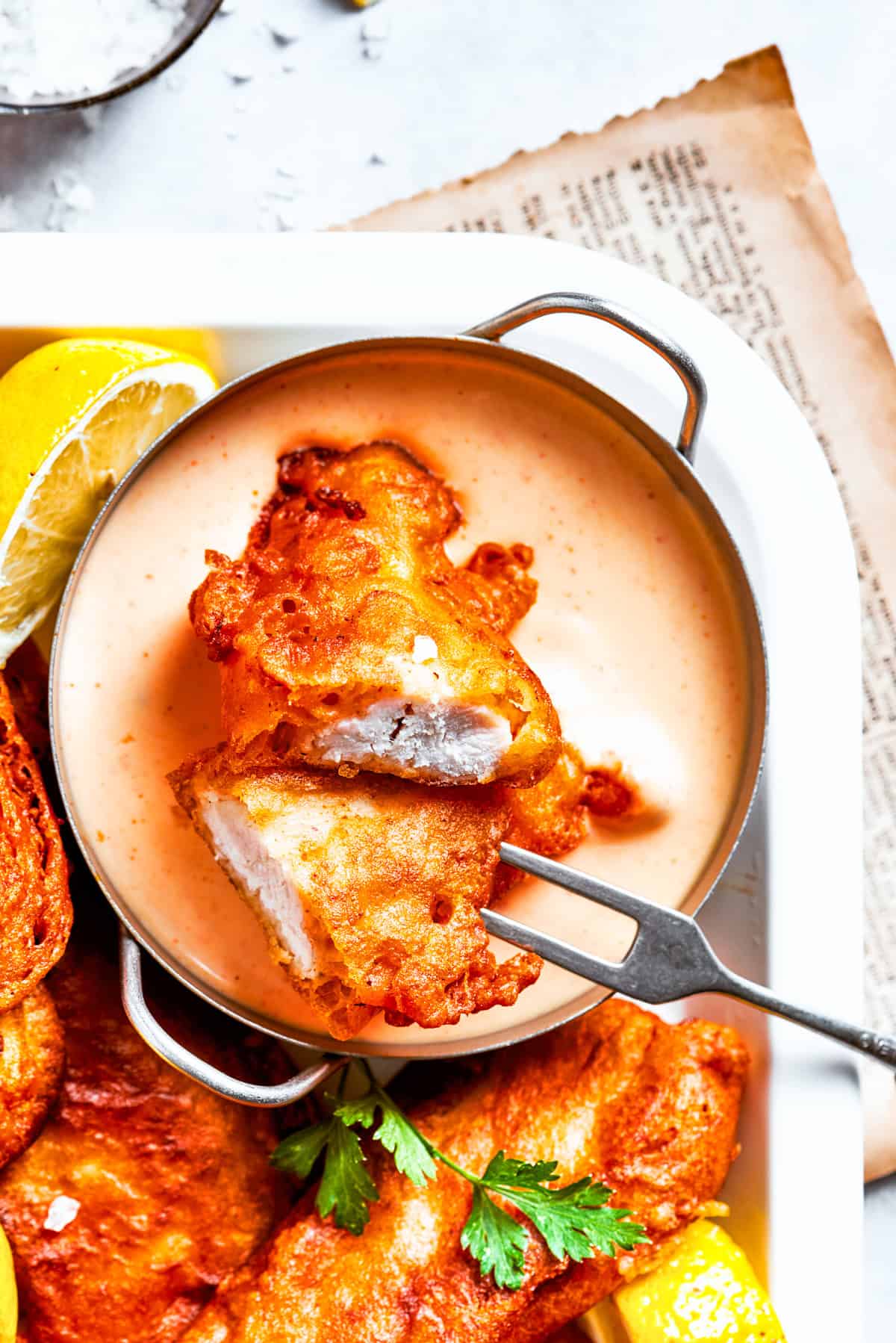 A platter of beer, battered chicken, and a bowl of sauce.