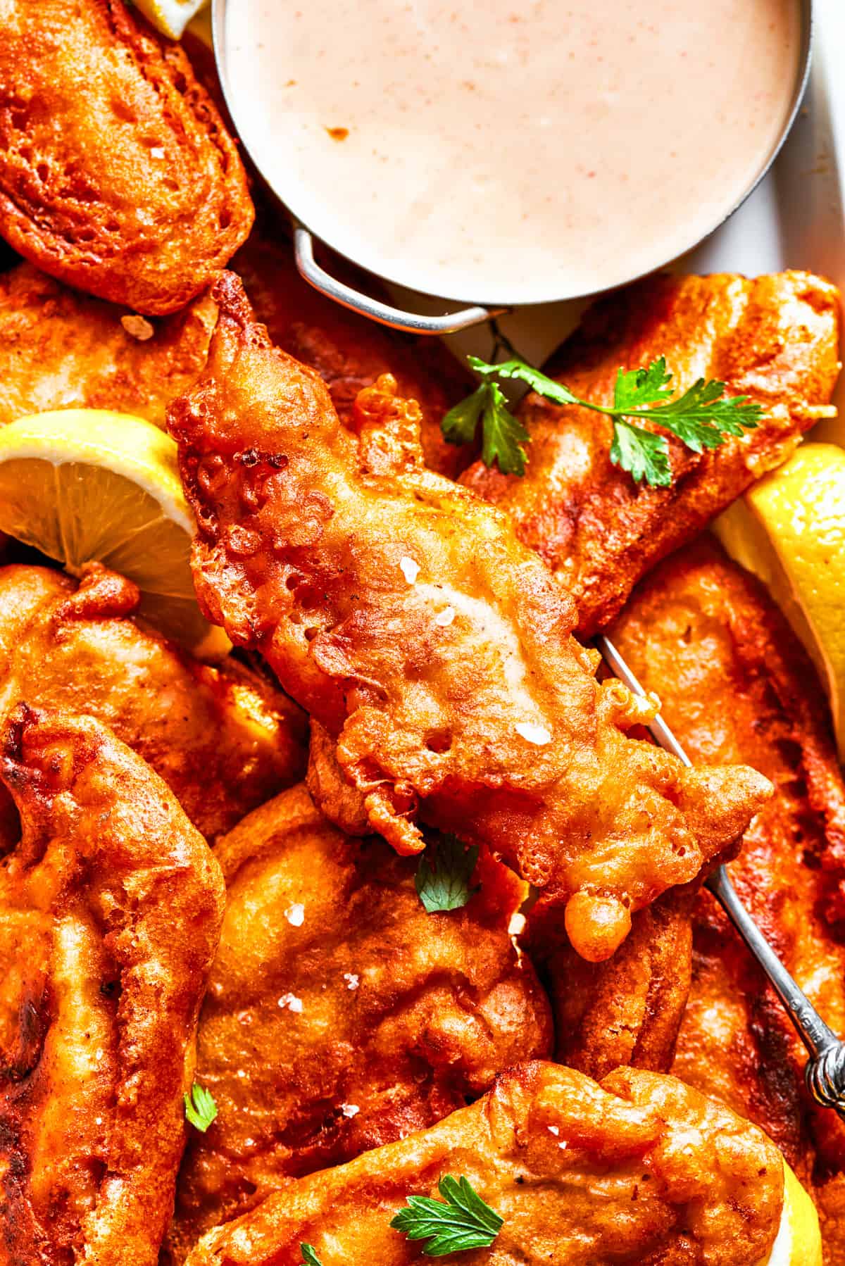 Closeup photo of battered chicken arranged on a plate with a bowl of dipping sauce.