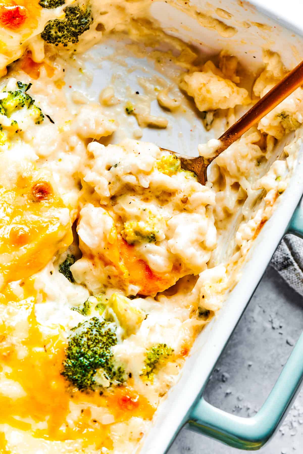 A serving utensil scoops into a pan of broccoli & rice casserole.