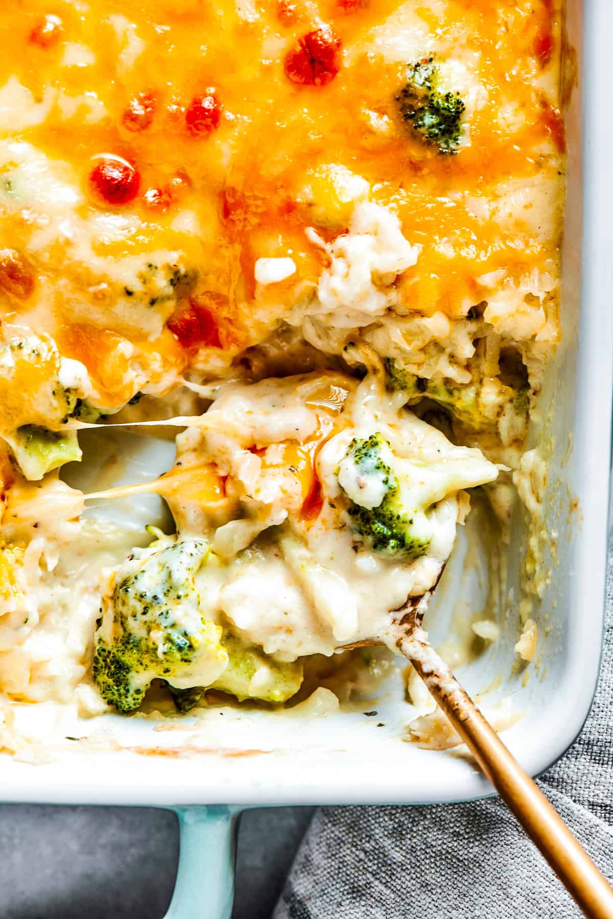 A serving spoon scooping out broccoli rice casserole from a baking dish.