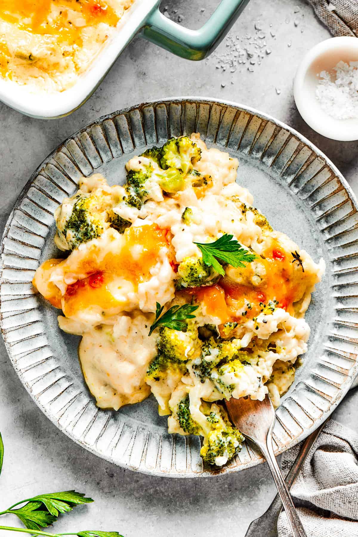 A serving of broccoli & rice casserole on a blue plate with a fork.