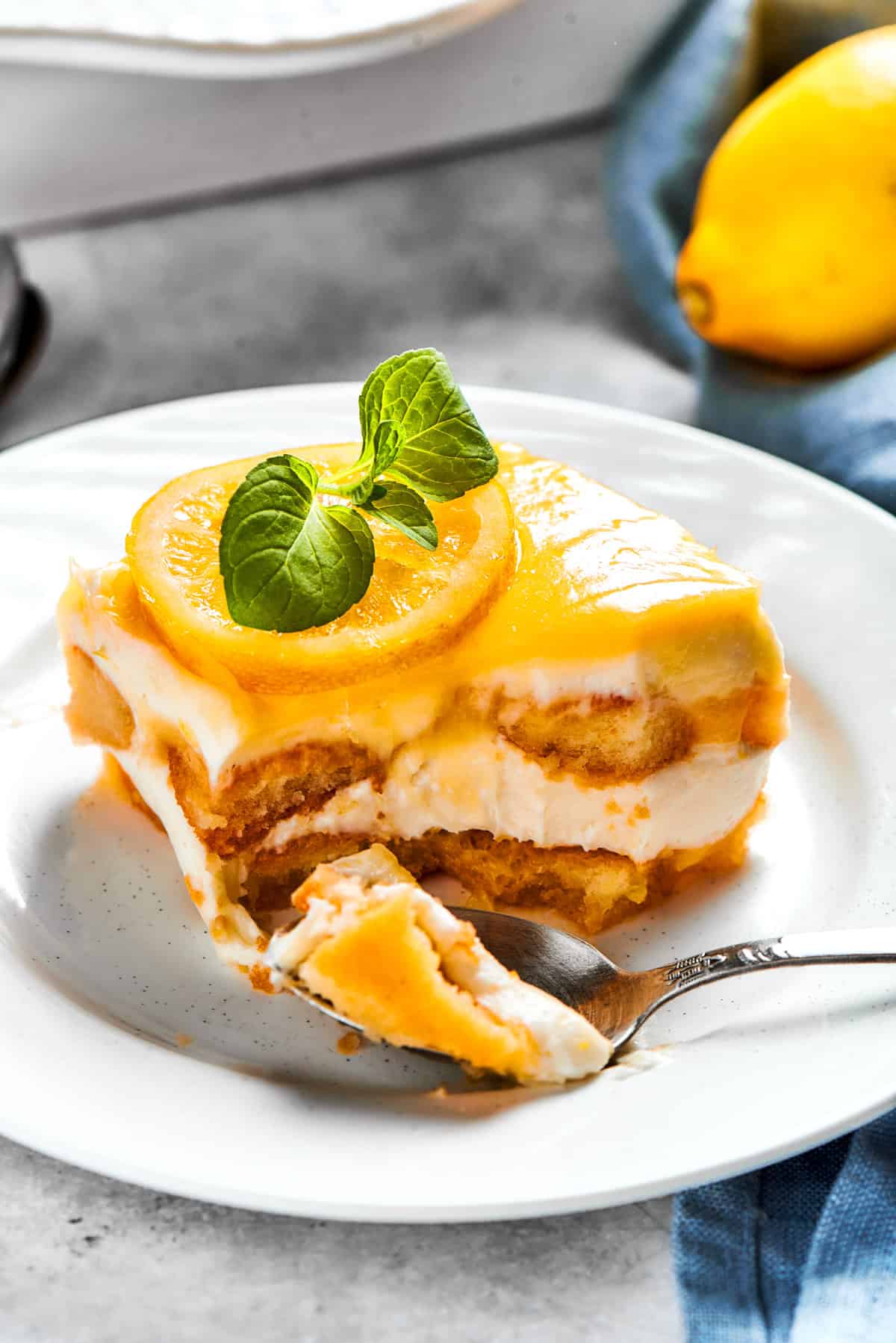 A fork cutting into a portion of lemon tiramisu served on a small dessert plate.