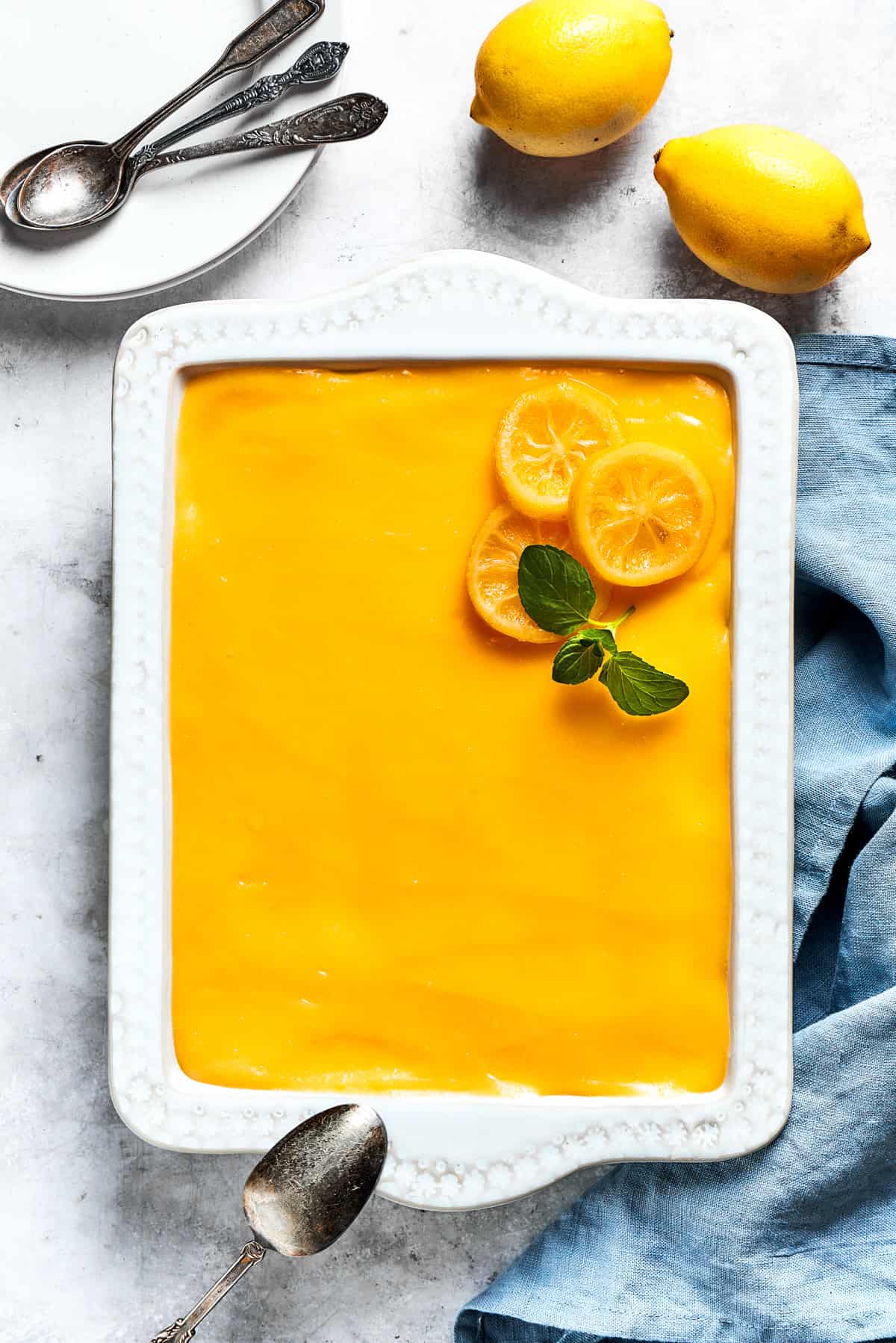 Overhead image of a dish with lemon tiramisu and fresh lemons set next to it.