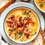 A bowl of Zuppa Toscana is served in bowls and garnished with crumbled bacon.