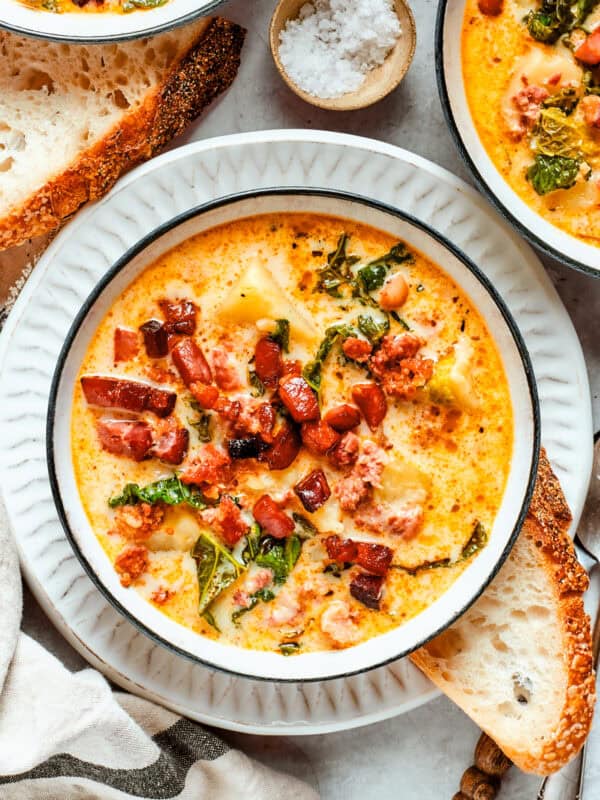 A bowl of Zuppa Toscana is served in bowls and garnished with crumbled bacon.