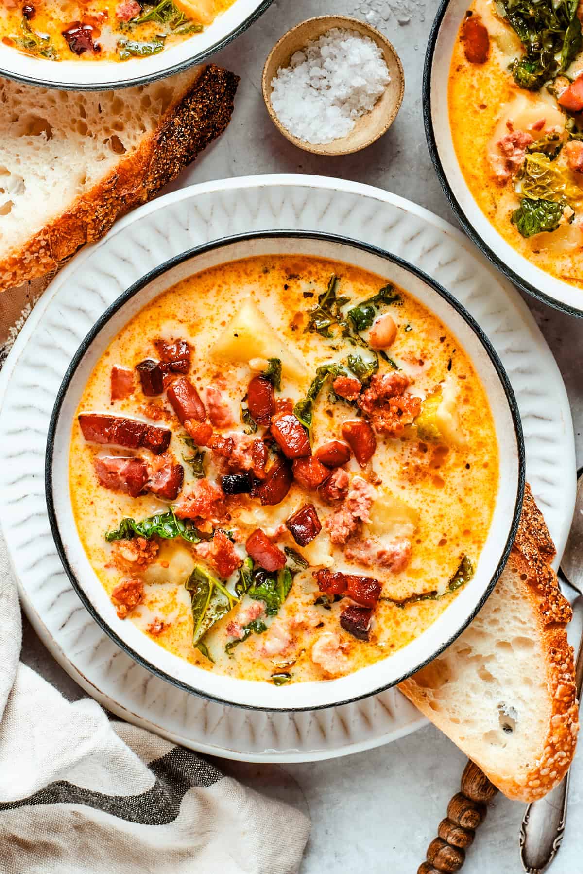 A bowl of Zuppa Toscana is served in bowls and garnished with crumbled bacon.