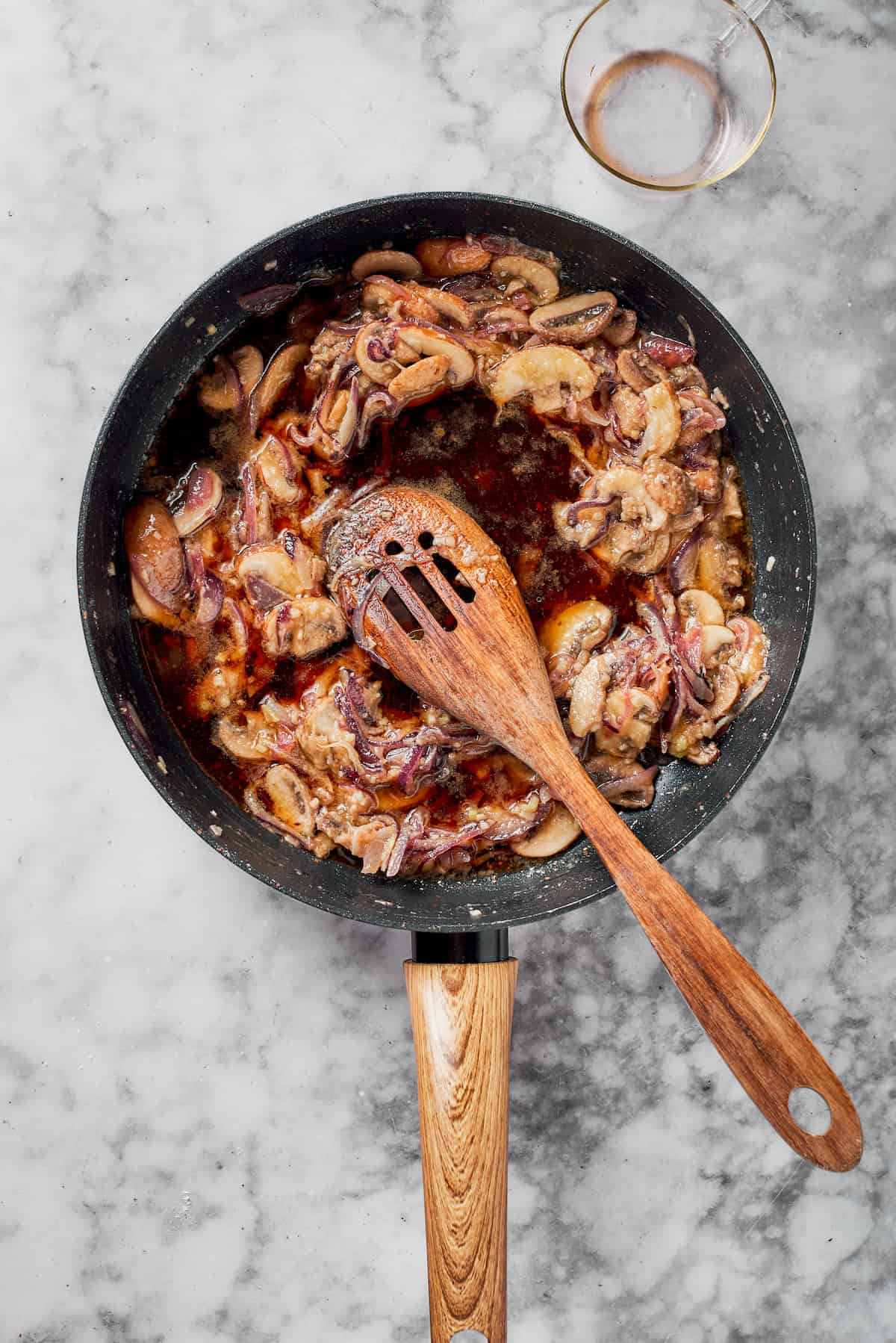 Adding wine to mushrooms in a skillet.