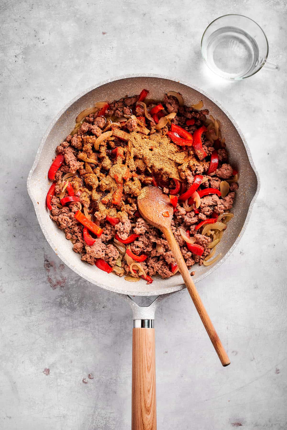 Adding taco seasoning to cooked beef and peppers.