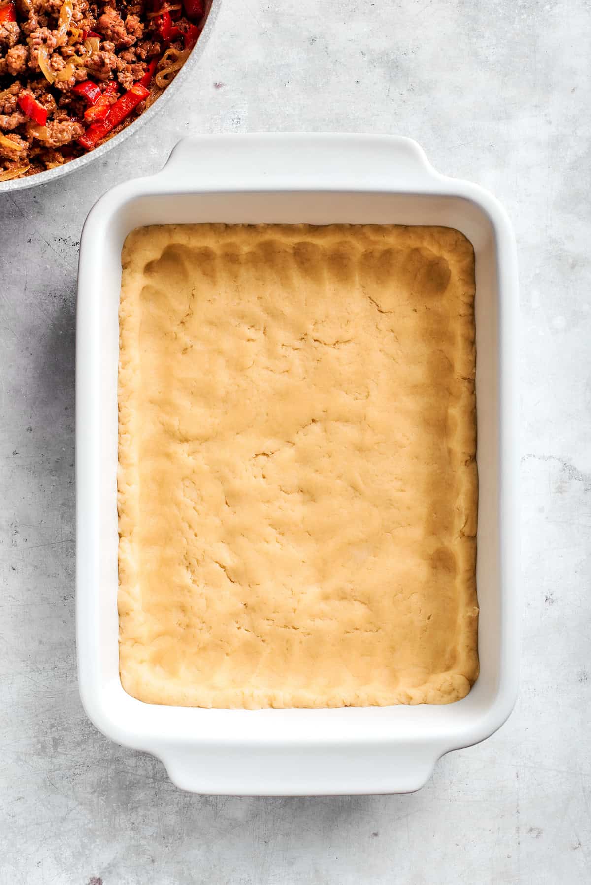 Pressing dough into a baking dish.