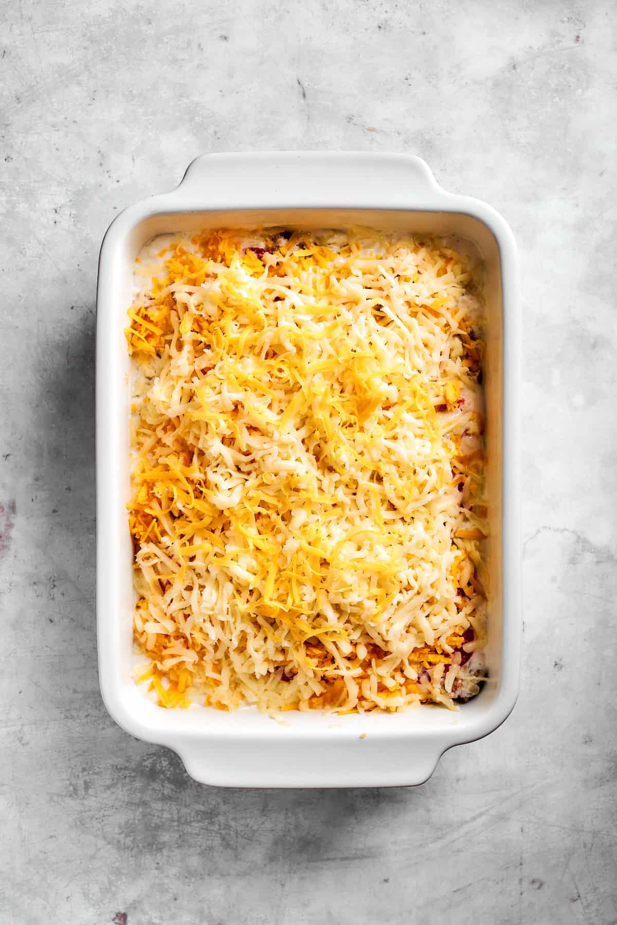 Cheese sprinkled on top of John Wayne Casserole ready to bake.