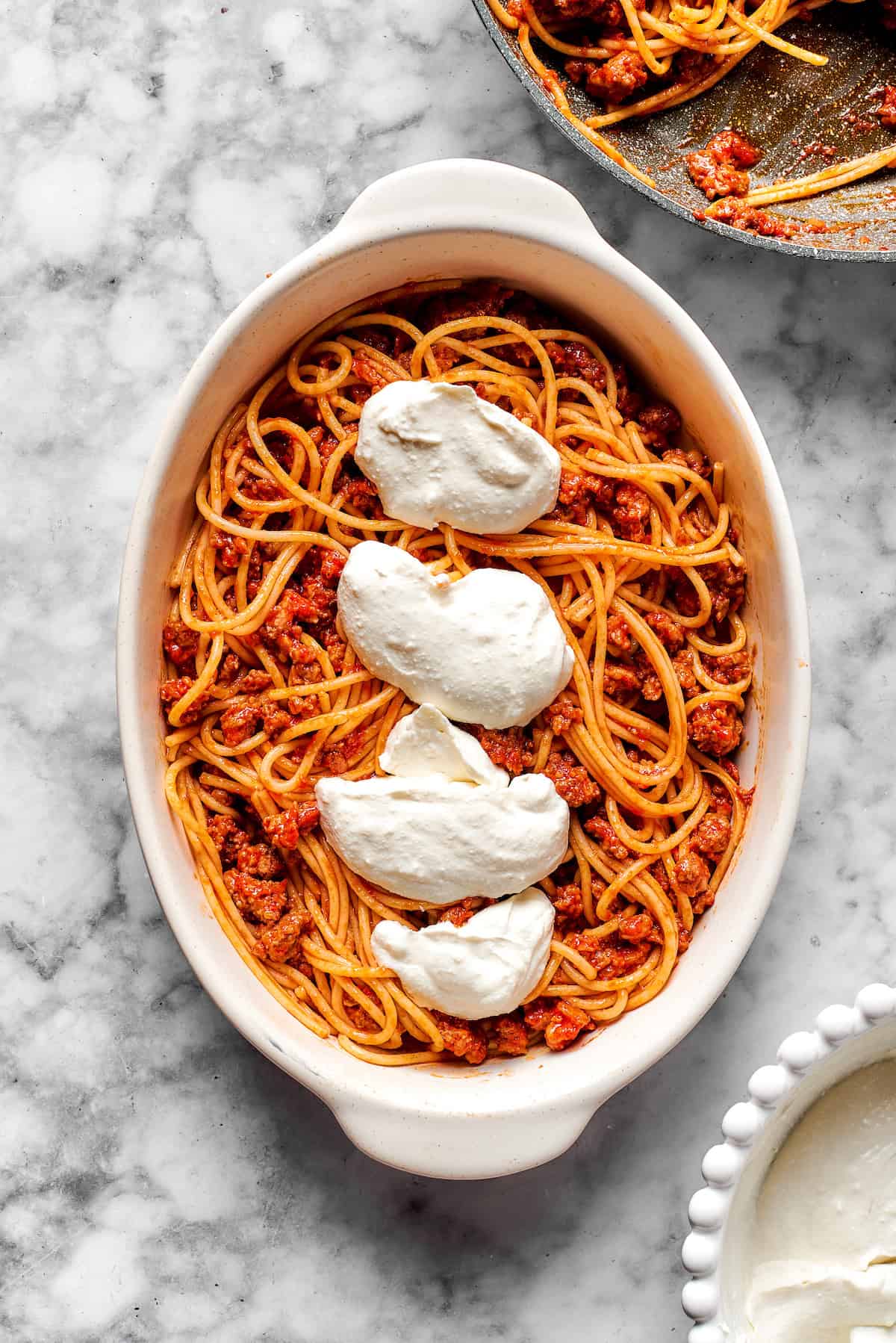 Adding cheese mixture on top of spaghetti.