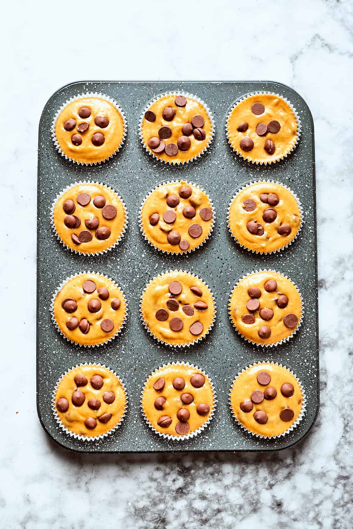 Pumpkin chocolate chip muffin batter in a muffin tin.