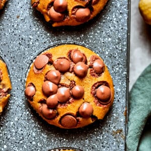 Three pumpkin chocolate chip muffins in a muffin tin.