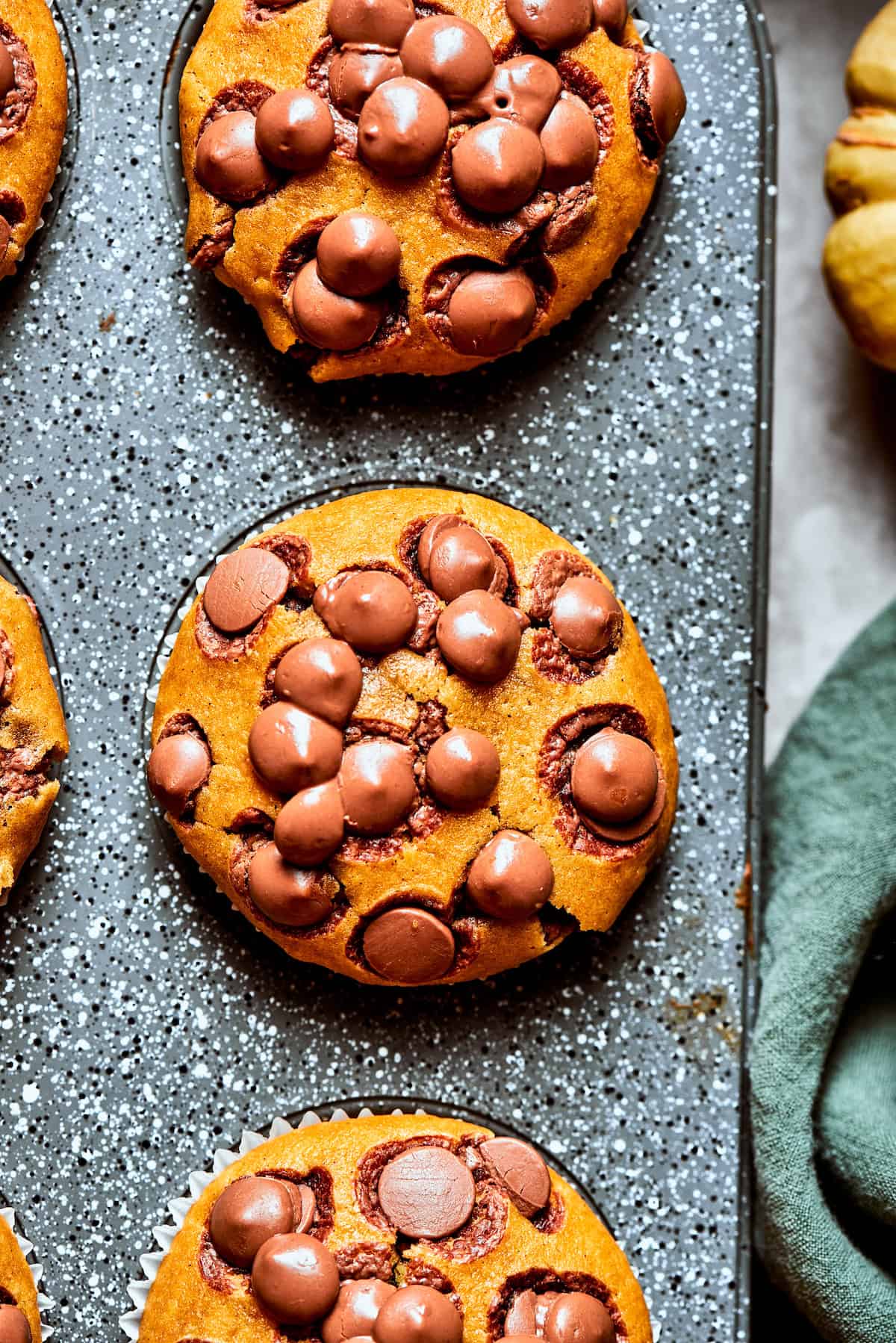 Three pumpkin chocolate chip muffins in a muffin tin.