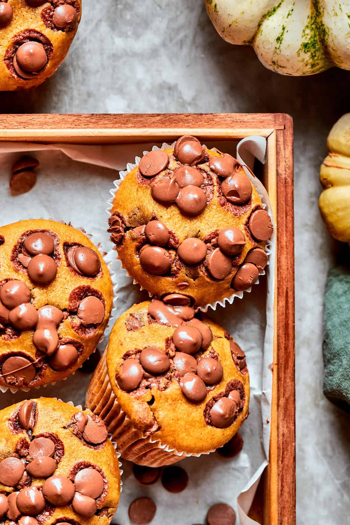 Four pumpkin chocolate chip muffins on a tray.