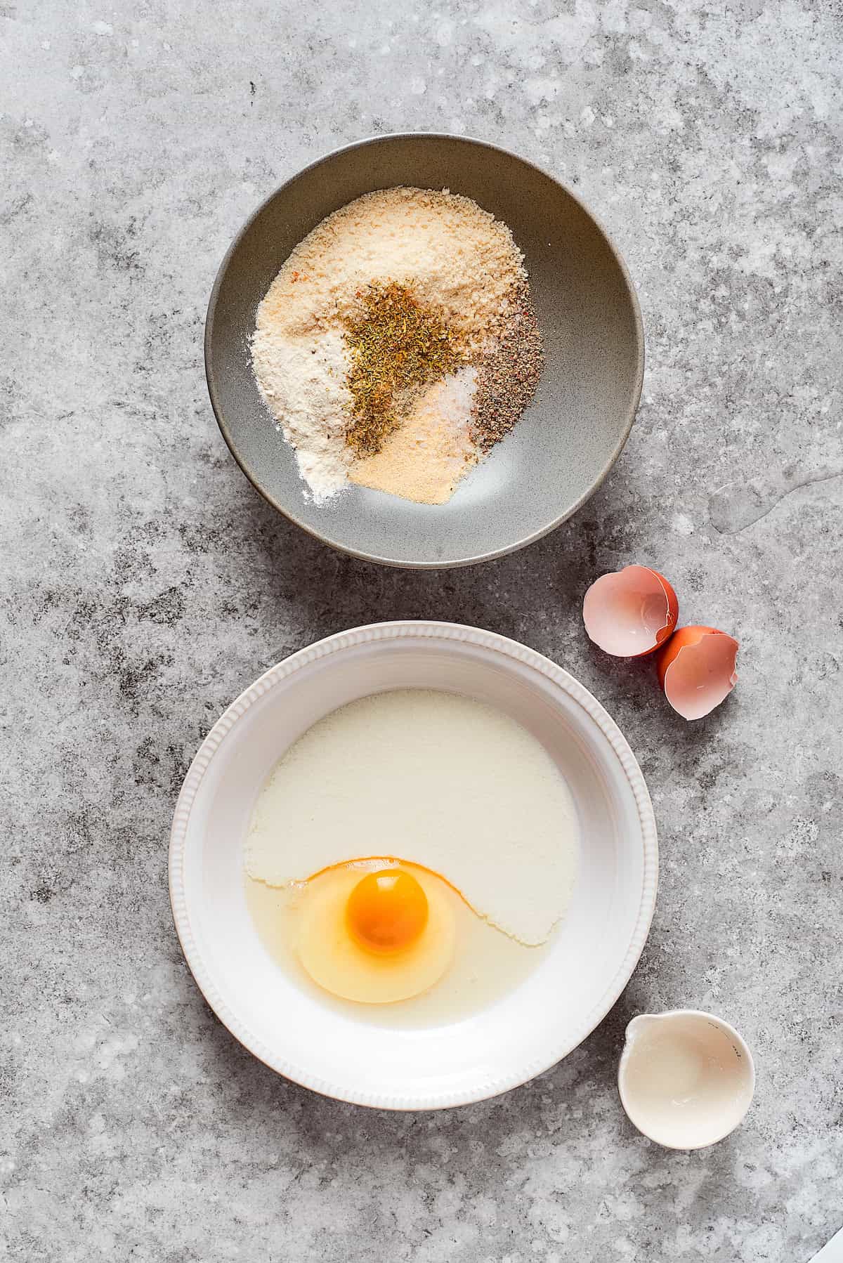 A bowl of breadcrumbs and seasoning and a bowl of egg.