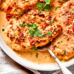 A serving spoon lifts out a portion of smothered chicken.