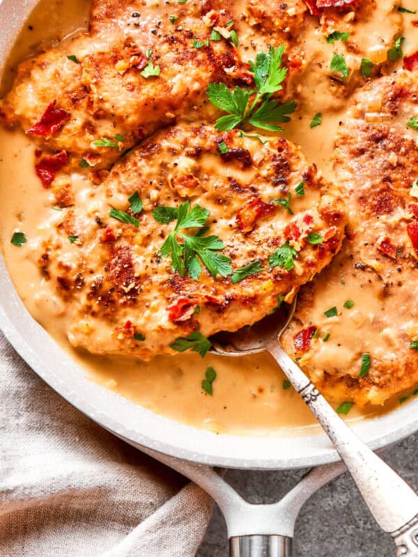 A serving spoon lifts out a portion of smothered chicken.