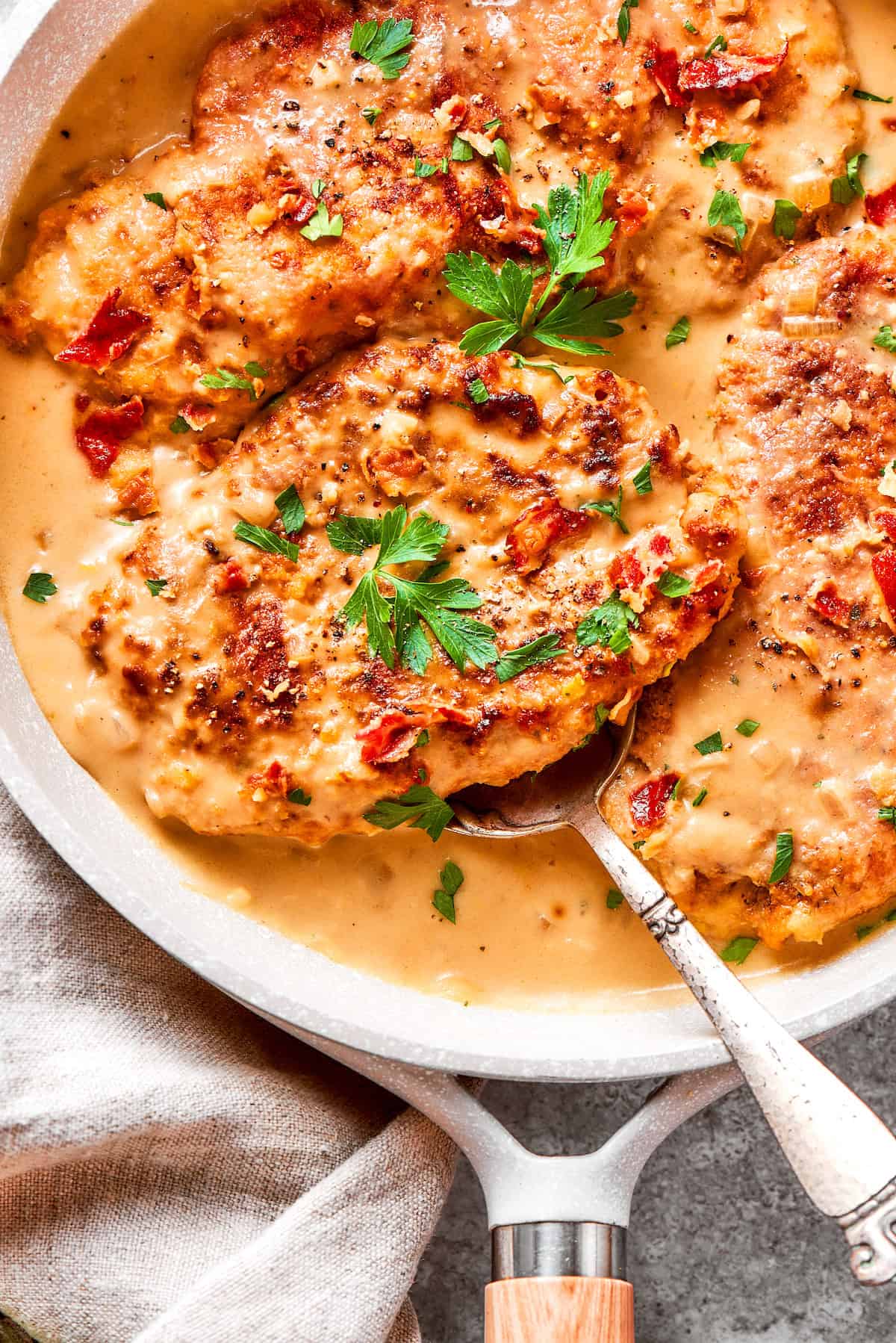 A serving spoon lifts out a portion of smothered chicken.