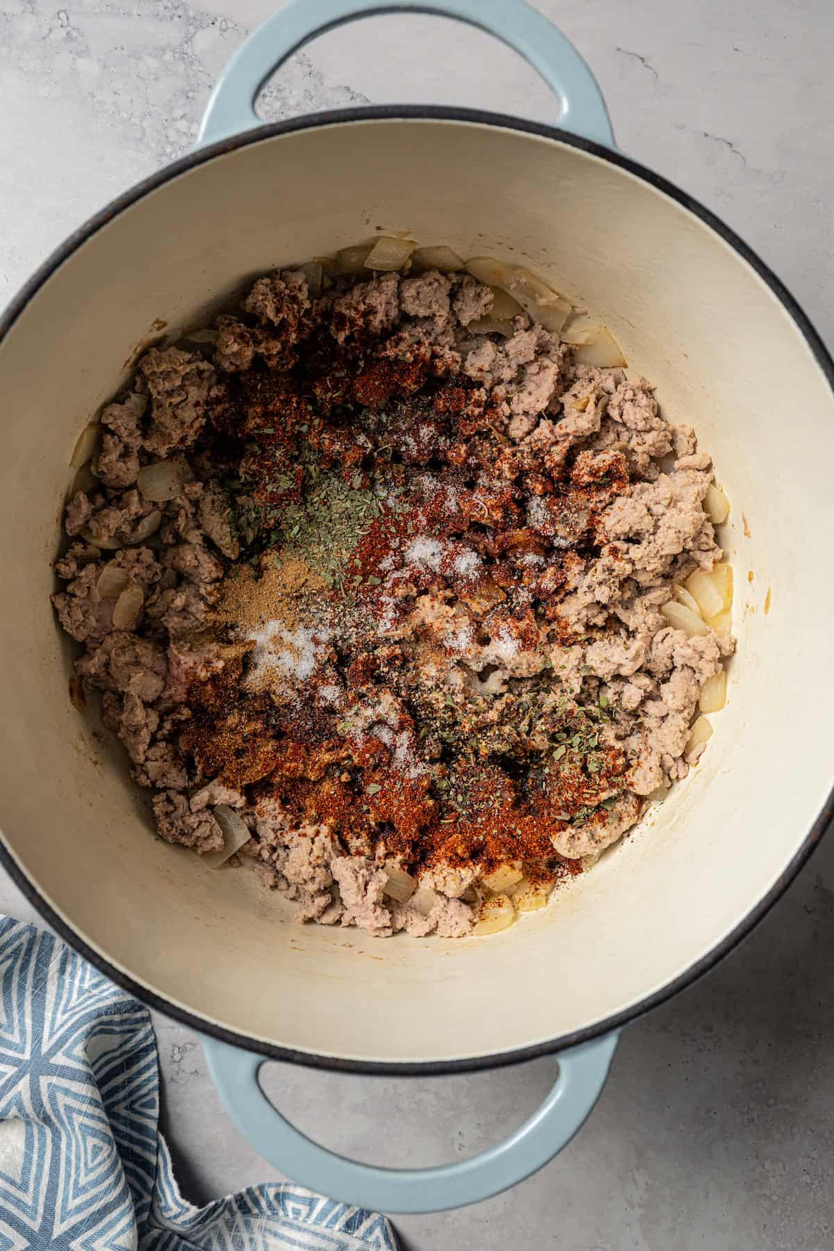 Seasoning added to browned ground turkey in a large pot.