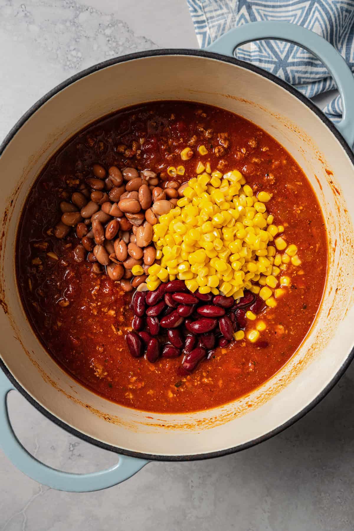 Canned corn and beans added to a pot with turkey chili.