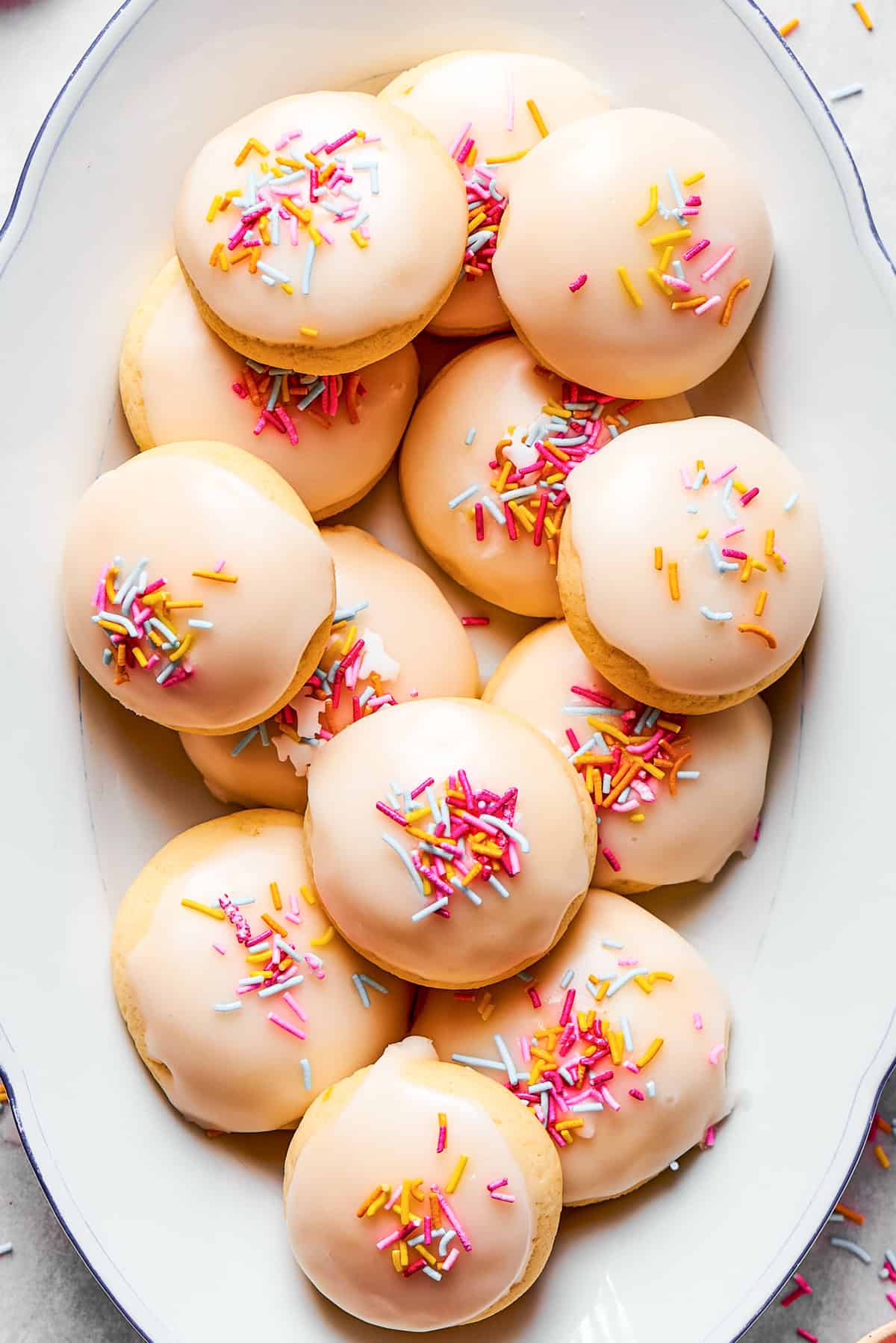 Sprinkles top anginetti cookies arranged on a plate.