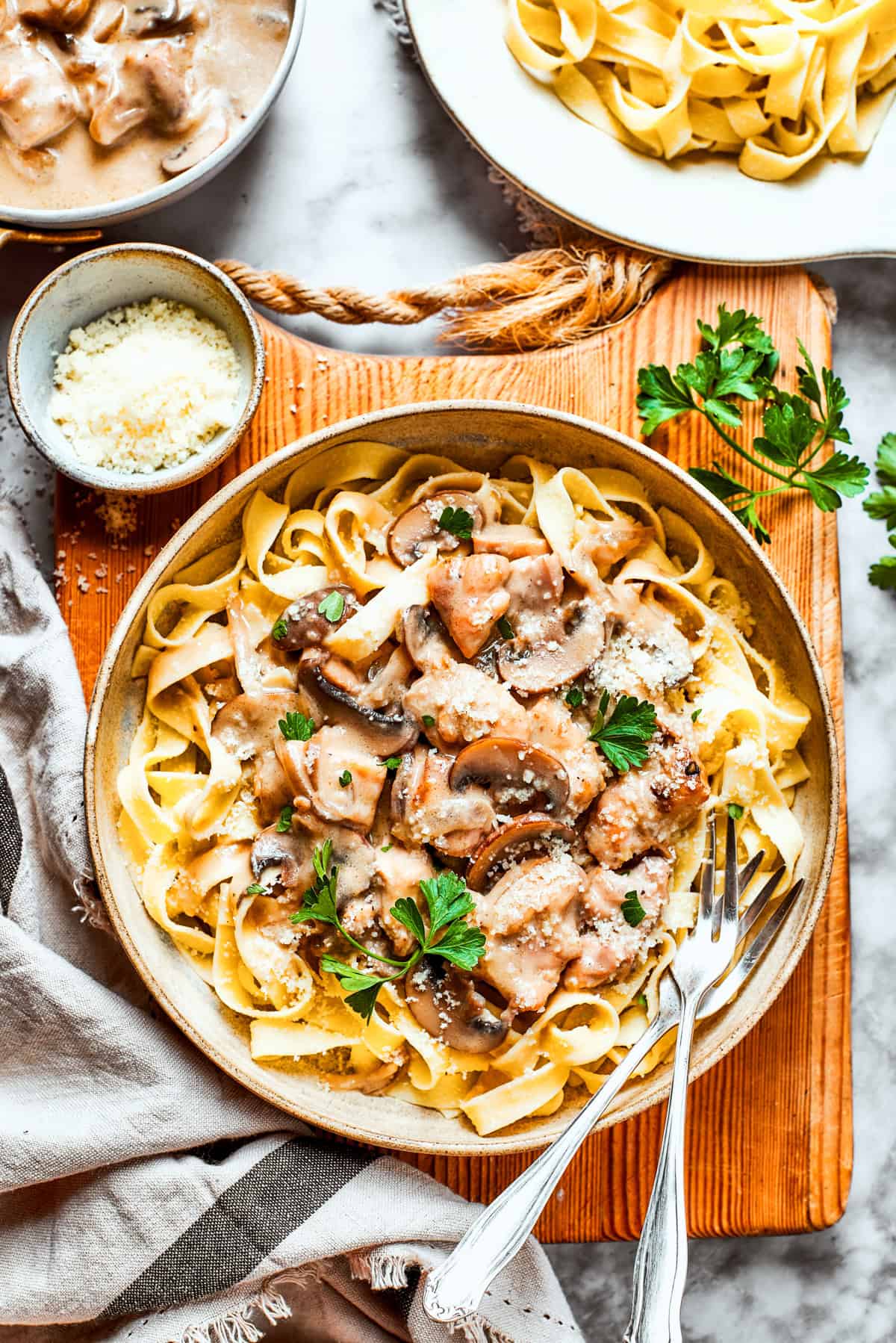 Bowl of chicken fettuccine placed on a wooden board.