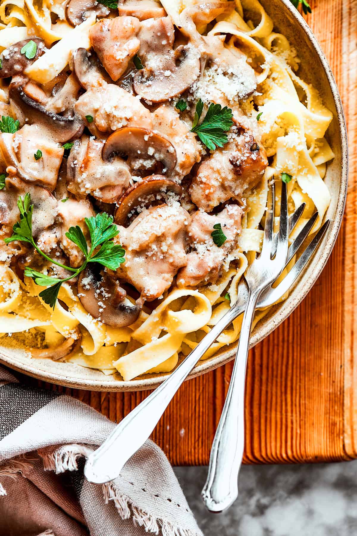 A bowl of chicken marsala noodles with two forks resting inside the bowl.