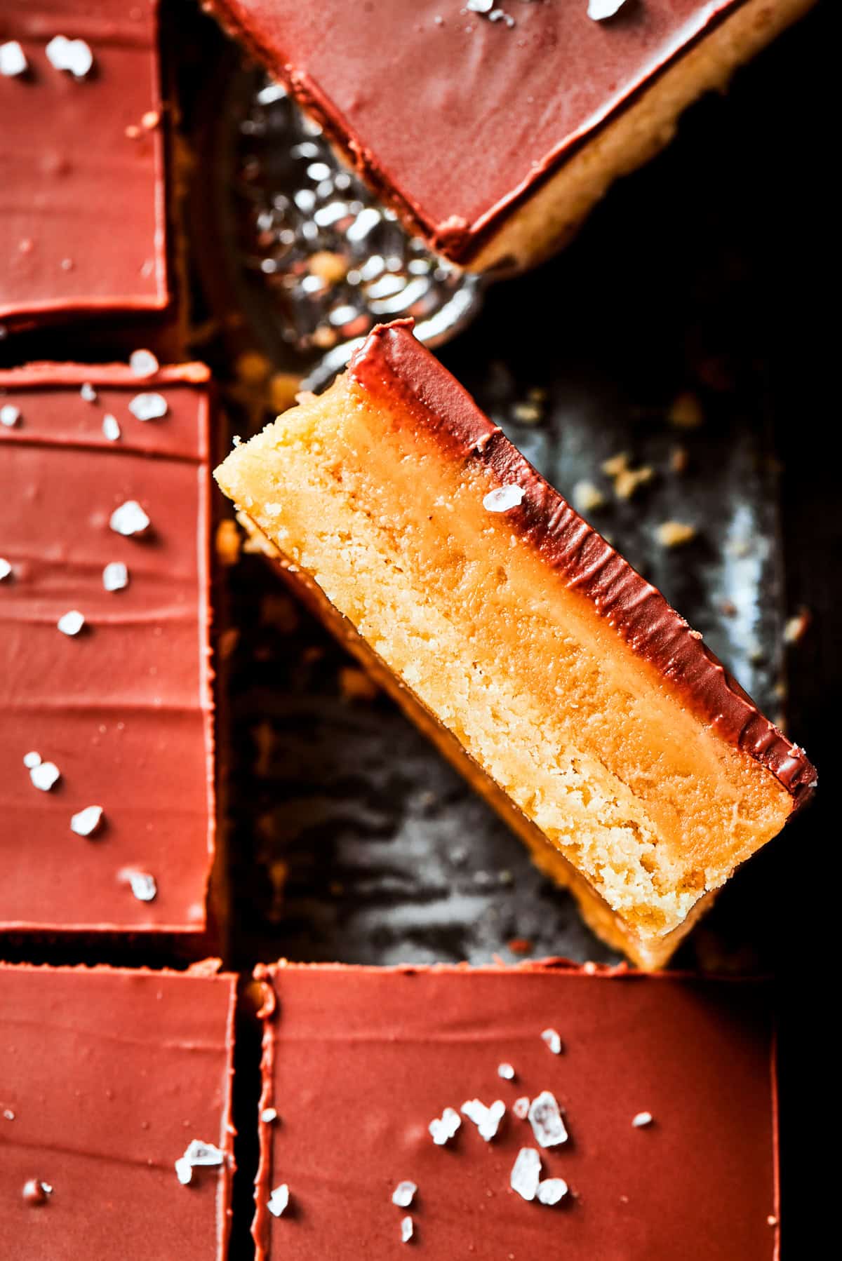 A bar is turned on its side on top of a pan of millionaire bars.