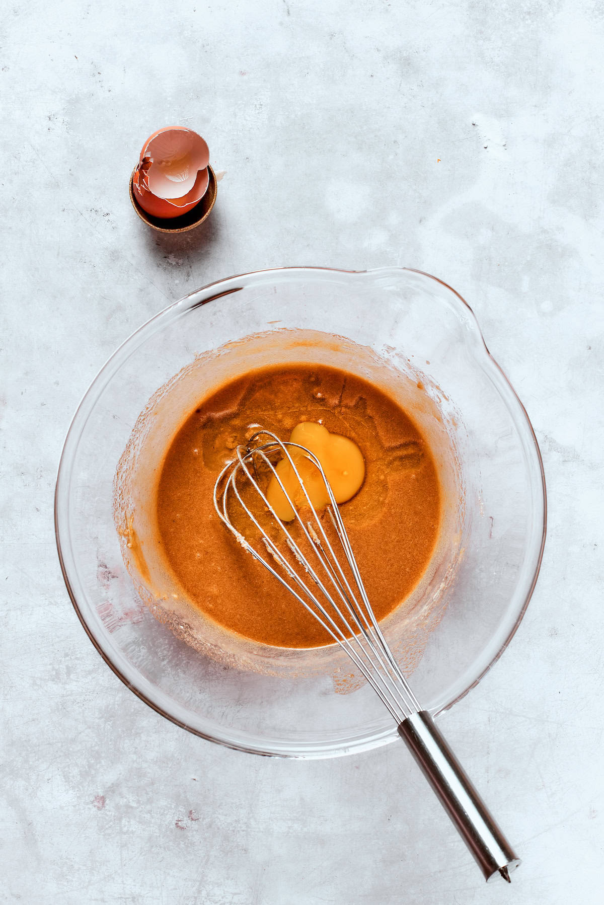 An egg is whisked into apple cider donut batter.