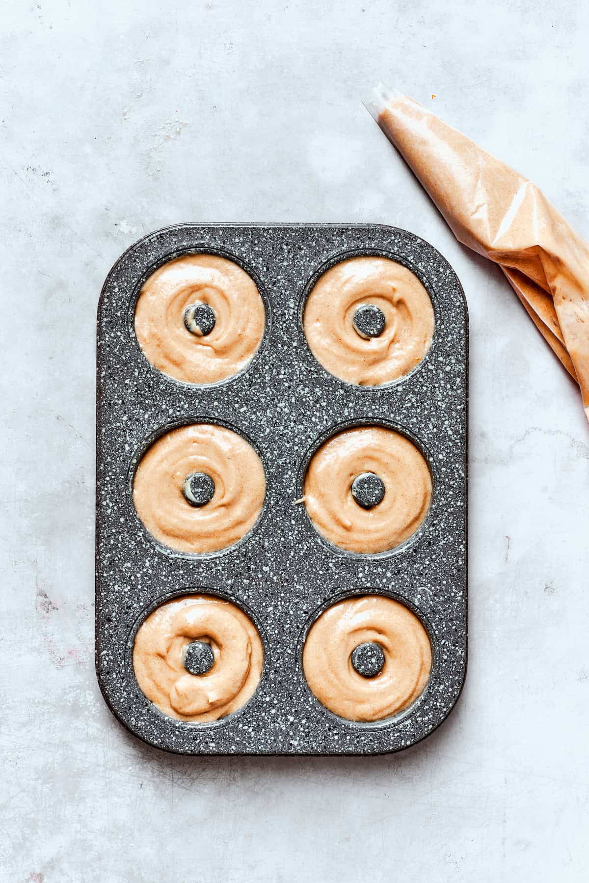 A donut pan with batter for apple cider donuts.