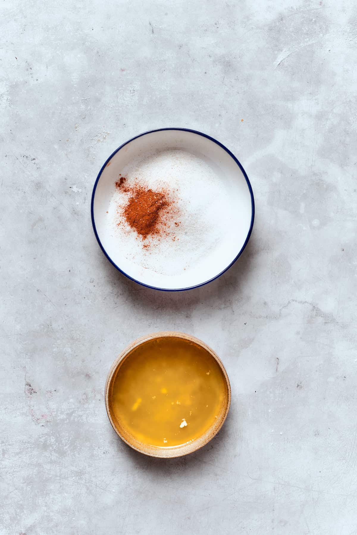 A bowl of melted butter and a bowl of sugar and cinnamon.