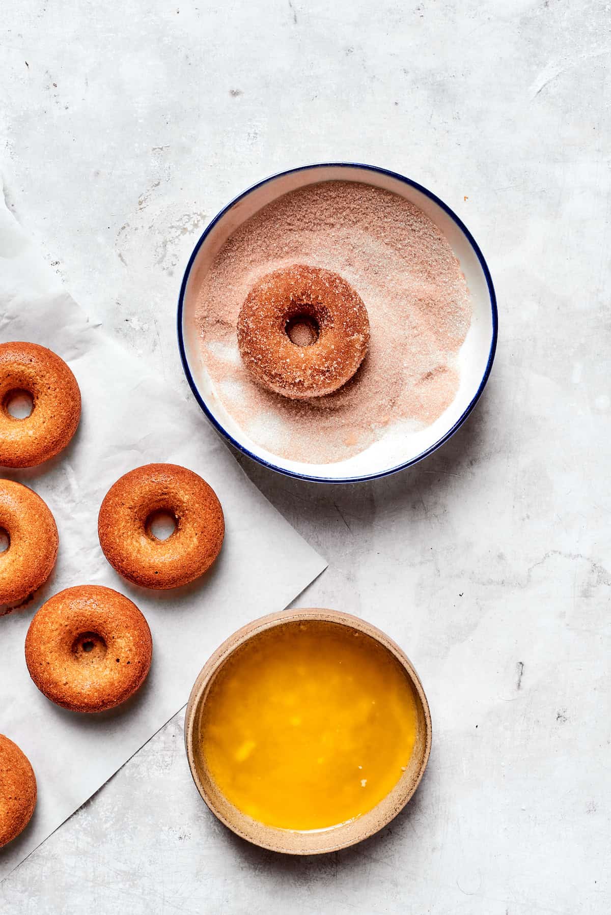 An apple cider donut dipped in a bowl of cinnamon sugar.